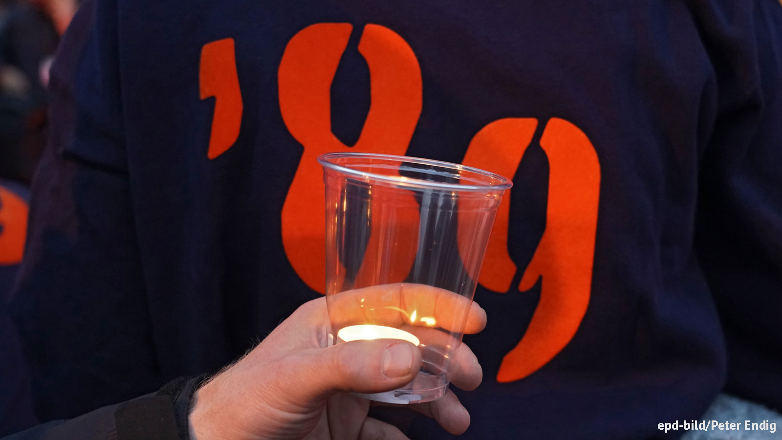 Bild mit einem Windlicht und einer Person, die ein Sweatshirt mit dem Aufdruck "'89" trägt.