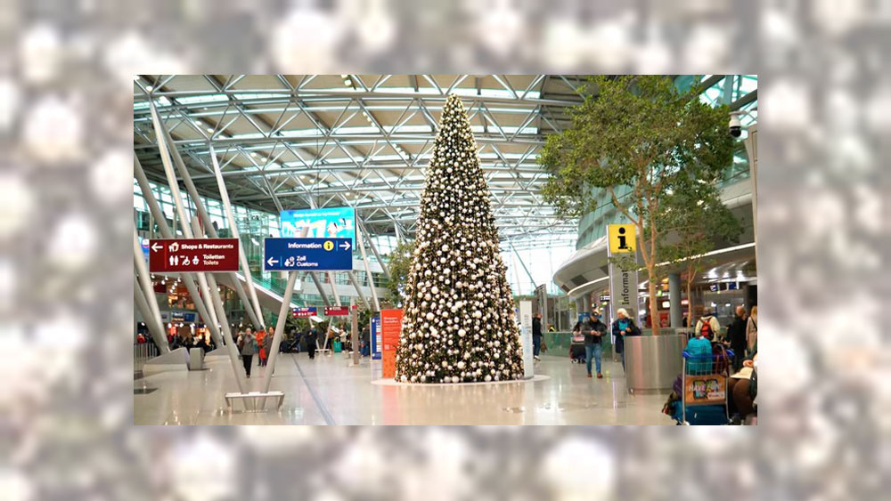 Flughafenhalle mit Weihnachtsbaum, Reisende