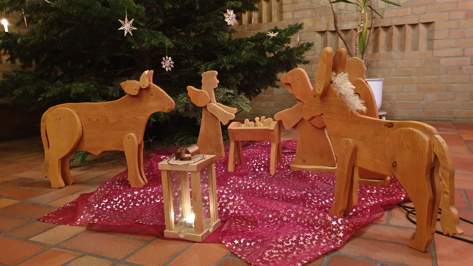 Krippenfiguren aus Holz in der Kirche, Laterne und Weihnachtsbaum