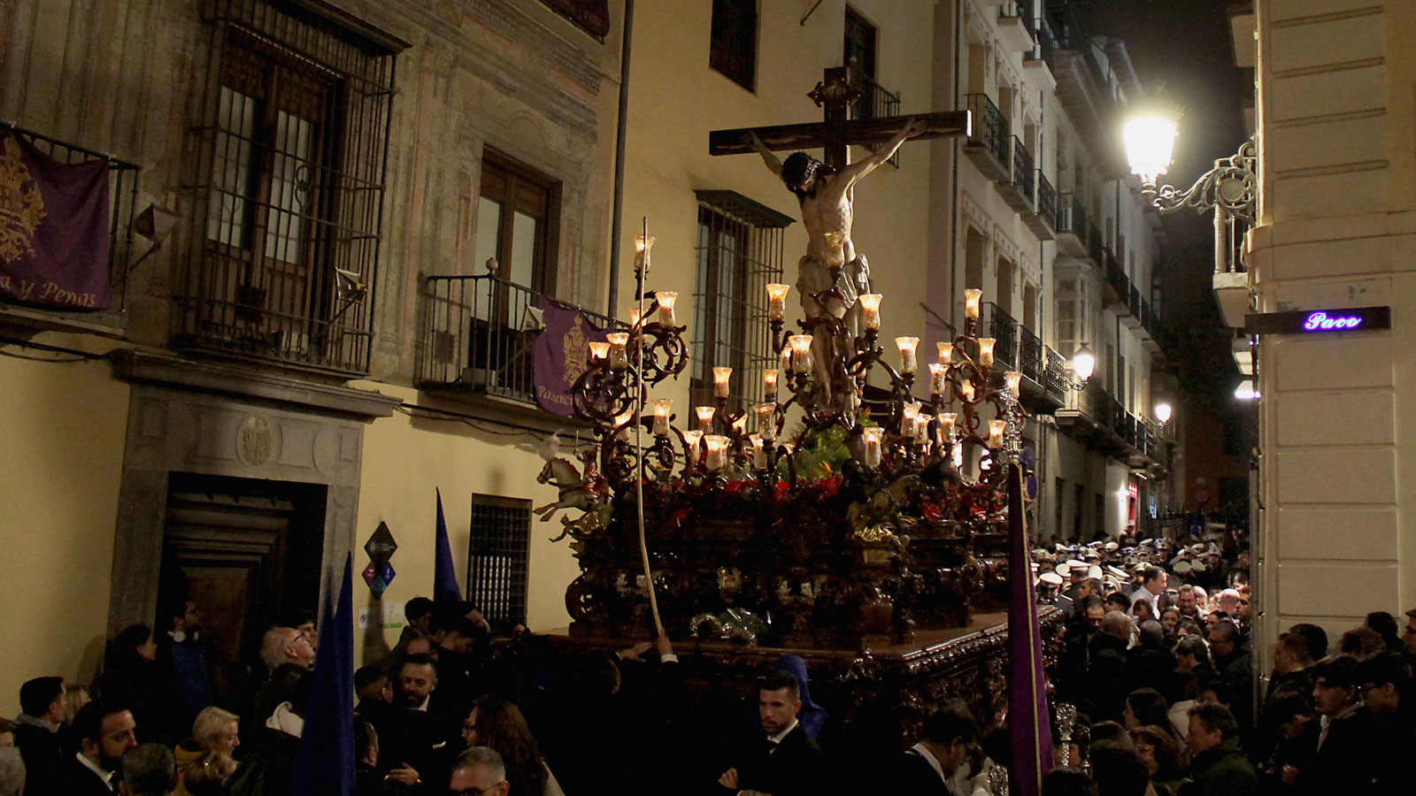Prozessionswagen mit Jesus am Kreuz in einer engen Gasse, umringt von vielen Menschen