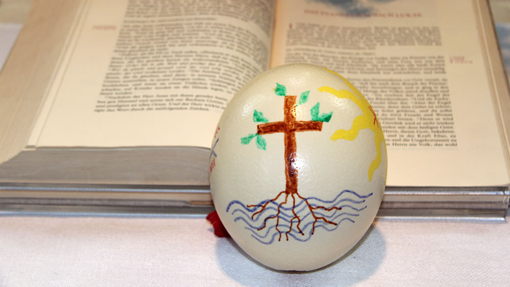 aufgeschlagene Bibel, darauf ein mit Ostermotiven bemaltes Straußenei